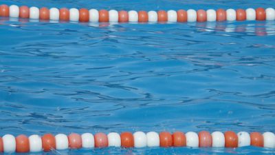 Blått vatten i en bassäng och linor som gränsar av olika simbanor.