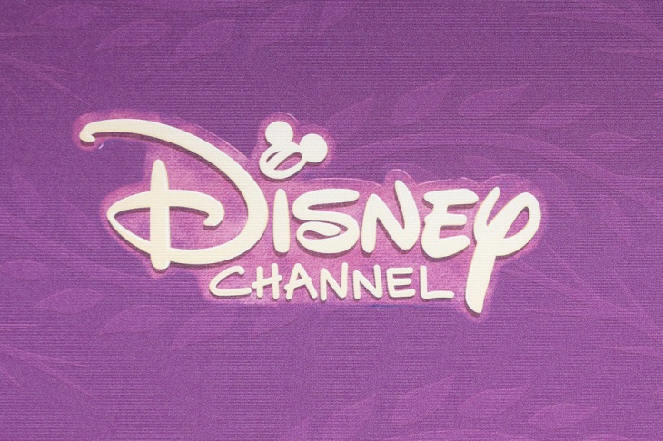Det står "Disney channel" mot en lila bakgrund med vit lekfull text. I:ets prick är ett musse pigg-huvud.