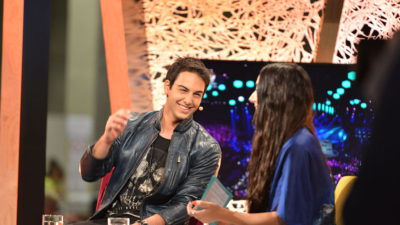 Bild på Darin som sitter i en fåtölj och blir intervjuad. Han skrattar och gör en gest med handen.