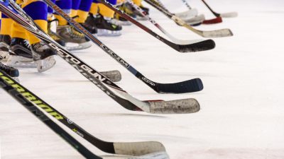 Ishockeyspelare står uppradade på isen med sina klubbor.